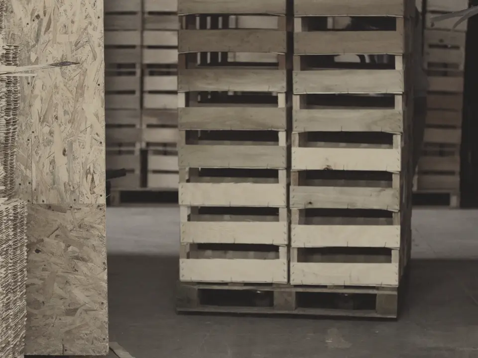 Wooden shipping crates stacked on pallets in a warehouse.